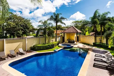 a swimming pool with chairs and a house at Beachfront Oceanview Private Jacuzzi & Full ktcn in Tamarindo