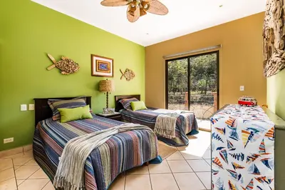 three beds in a room with green walls at Amazing Condo Across the Street from the Beach in Tamarindo