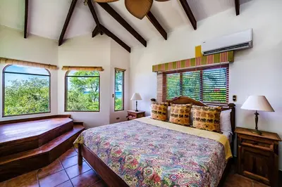 a bedroom with a large bed and two windows at Beachfront Ocean view terrace right on the beach in Tamarindo