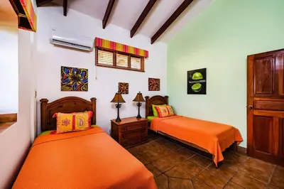 a bedroom with two beds with orange sheets at Beachfront Ocean view terrace right on the beach in Tamarindo