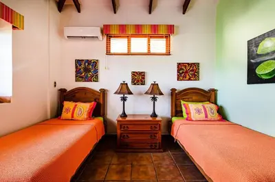 two beds in a room with orange sheets at Beachfront Ocean view terrace right on the beach in Tamarindo