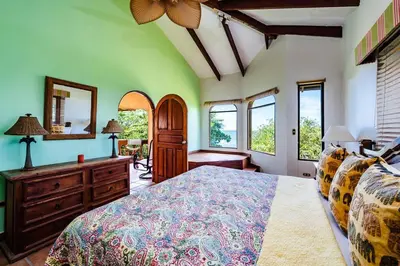 a bedroom with a bed and a dresser and windows at Beachfront Ocean view terrace right on the beach in Tamarindo