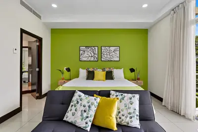 a green bedroom with a bed and a couch at Pura vida charm, canopy views, block from beach in Tamarindo