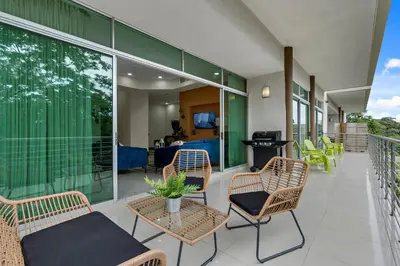 a balcony with chairs and tables and a living room at Pura vida charm, canopy views, block from beach in Tamarindo