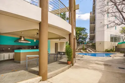 an external view of a building with a swimming pool at Pura vida charm, canopy views, block from beach in Tamarindo