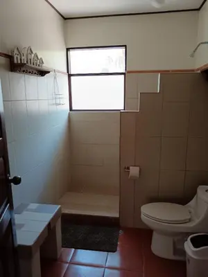 a bathroom with a toilet and a tub and a window at Casa Amapola in La Cruz