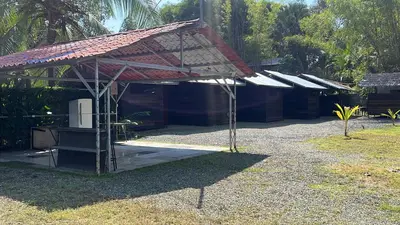 a building with a red roof with a table and chairs at Cabañas MOHES ballena in Uvita