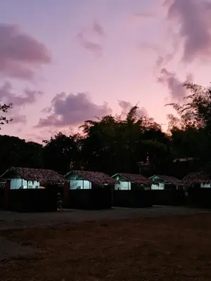 a group of huts with a sunset in the background at Cabañas MOHES ballena in Uvita