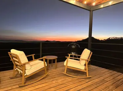 two chairs and a table on a deck with a view at GoldenView+ Aire acondicionado+Jacuzzi (a 15 km de Monteverde) in Monteverde Costa Rica