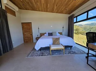 a bedroom with a bed and a large window at GoldenView+ Aire acondicionado+Jacuzzi (a 15 km de Monteverde) in Monteverde Costa Rica