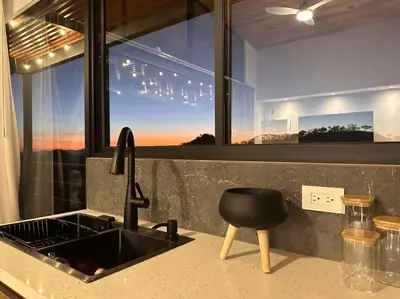 a kitchen counter with a sink and a black stool at GoldenView+ Aire acondicionado+Jacuzzi (a 15 km de Monteverde) in Monteverde Costa Rica