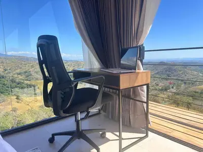 a desk with a computer and a chair in front of a window at GoldenView+ Aire acondicionado+Jacuzzi (a 15 km de Monteverde) in Monteverde Costa Rica
