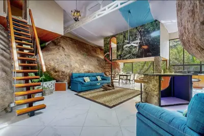 a living room with blue furniture and a stone wall at Rocka Verde Retreat 8th Wonder of the World in Rivas