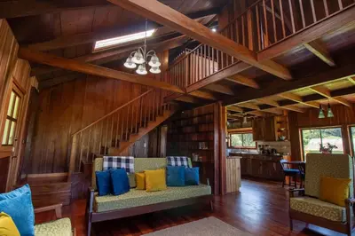 a living room with wooden walls and a staircase with blue and yellow pillows at Mountain Wonders Chalet in Monteverde Costa Rica