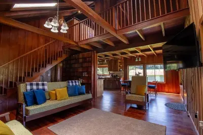 a living room with a couch and a staircase at Mountain Wonders Chalet in Monteverde Costa Rica