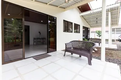a bench sits on the porch of a house at Rio Celeste Birds Garden Apartment, Aire Acondicionado, comodidad y privacidad en un entorno natural 2 in Upala