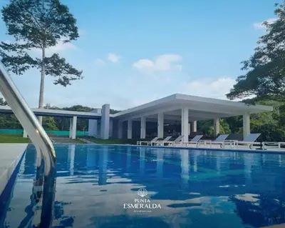 a swimming pool with chairs and a building at Apartamento hermoso Playa Mantas in Punta Leona