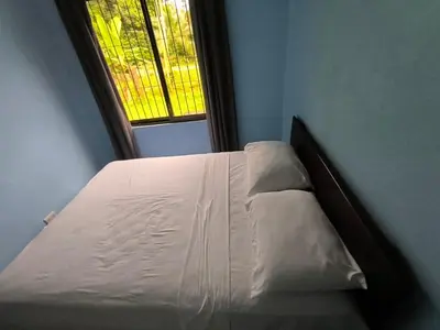 a white bed in a room with a window at La Martha in Sarapiquí