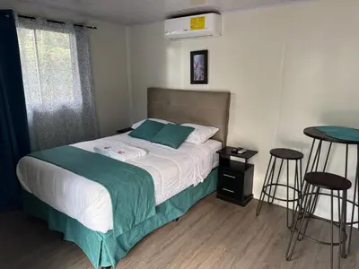 a bedroom with a bed and two stools at Macaw Paradise in Jacó