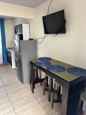a small kitchen with a table and a refrigerator at Macaw Paradise in Jacó