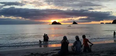 a group of people sitting on the beach watching the sunset at Beach, Oceanfront 2BR, 2BA Condo in Las Catalinas - Plaza Mercado 12 in Playa Danta