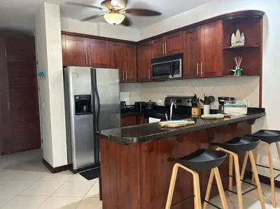 a kitchen with wooden cabinets and a stainless steel refrigerator at Villa Ela en Playa Herradura in Herradura