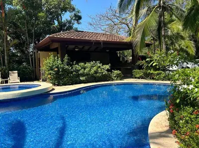 a large blue swimming pool in front of a house at Villa Ela en Playa Herradura in Herradura