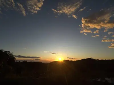 a sunset with the sun setting over a hill at Casa Típica La Cruz in Monteverde Costa Rica