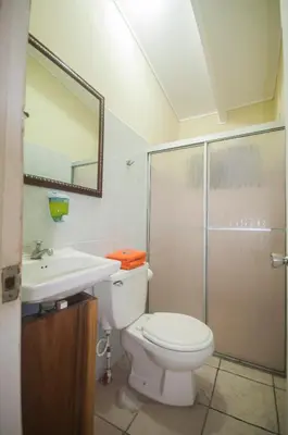 a bathroom with a toilet and a sink and a shower at Cadillac Rock Beach Hotel in Jacó