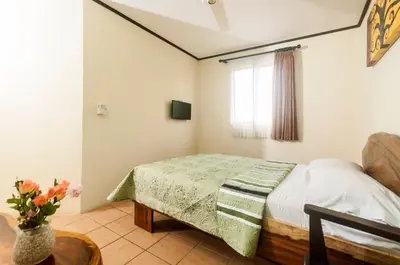 a bedroom with a bed and a vase of flowers at Cadillac Rock Beach Hotel in Jacó