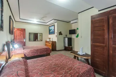 a hotel room with two beds and a television at Cadillac Rock Beach Hotel in Jacó