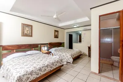 a bedroom with two beds and a bathroom at Cadillac Rock Beach Hotel in Jacó