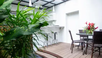 a patio with a table and chairs and plants at La Vela Boutique Hotel in Manuel Antonio
