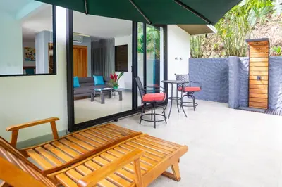 a patio with a bench and a table and chairs at La Vela Boutique Hotel in Manuel Antonio