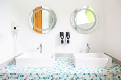 a bathroom with a sink and mirrors on the wall at La Vela Boutique Hotel in Manuel Antonio
