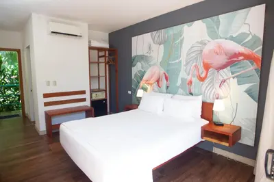a bedroom with a bed with a painting of flamingos at La Vela Boutique Hotel in Manuel Antonio