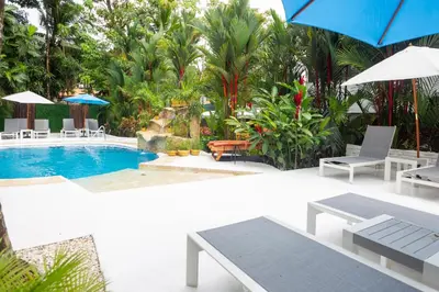 a pool with chairs and umbrellas in a resort at La Vela Boutique Hotel in Manuel Antonio