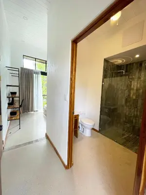a bathroom with a toilet and a glass shower door at Mar Botánico - Avellanas Beach Hotel in Playa Avellana