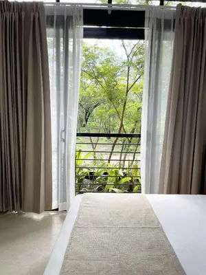 a bedroom with white curtains and a large window at Mar Botánico - Avellanas Beach Hotel in Playa Avellana