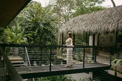 a woman in a white dress standing on a bridge at Mar Botánico - Avellanas Beach Hotel in Playa Avellana