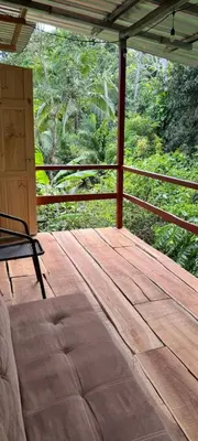 a wooden porch with a chair on a deck at Paso-lapas in Matapalo