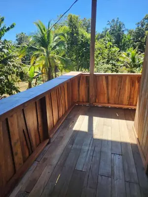 a wooden porch with a wooden fence and trees at Paso-lapas in Matapalo