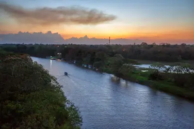 a boat on a river at sunset at Natural Lodge Caño Negro in Caño Negro