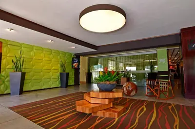 a lobby with a green wall and a table and chairs at Auténtico Hotel in San José