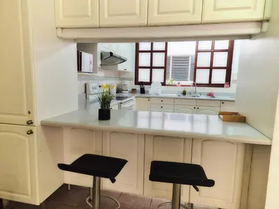a kitchen with white cabinets and a counter with two stools at Sabana Studios in San José