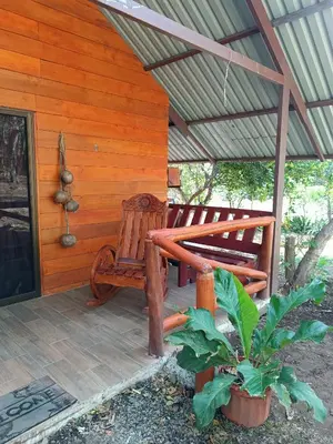 a porch with two wooden chairs and a plant at Cabaña Rincón de Curubandé in Liberia
