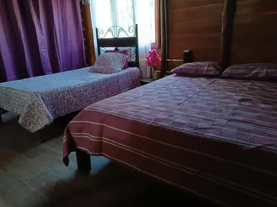 two beds in a room with purple curtains at Cabaña Rincón de Curubandé in Liberia