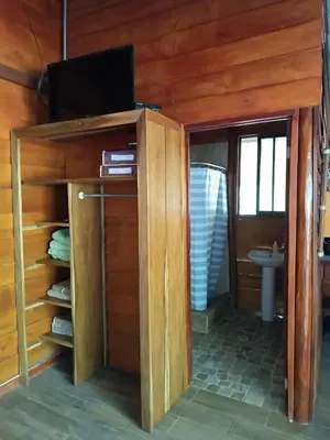 a bathroom with a tv on a wooden wall at Cabaña Rincón de Curubandé in Liberia