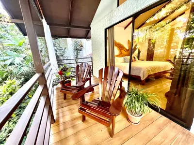 a balcony with two chairs and a bed in a bedroom at ECOTICA Boutique Hotel & Spa in Manuel Antonio