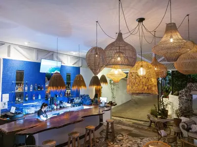 a bar with chandeliers and a man sitting at a counter at ECOTICA Boutique Hotel & Spa in Manuel Antonio